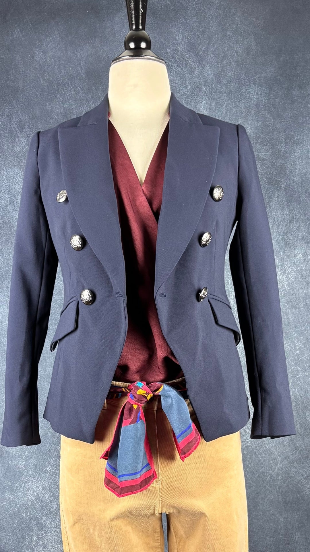 Foulard rectangulaire long Lanvin Paris, motifs floraux aux couleurs automnales. Vue de l'agencement avec le pantalon en velours côtelé beige sable, le blazer marine et la blouse pourpre.
