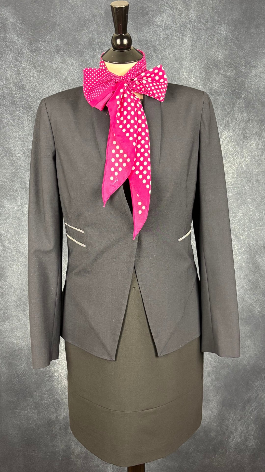 Foulard rose étroit à extrémités en pointe à pois blanc Vera. Vue de l'agencement avec le blazer Brunello Cucnelli et la robe Marc Aurel.
