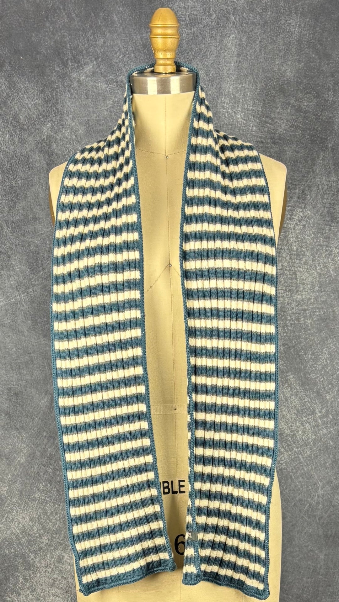 Foulard en tricot à rayures Chlorophylle, taille rectangulaire étroit. Vue du foulard, déposé sur les épaules du mannequin.