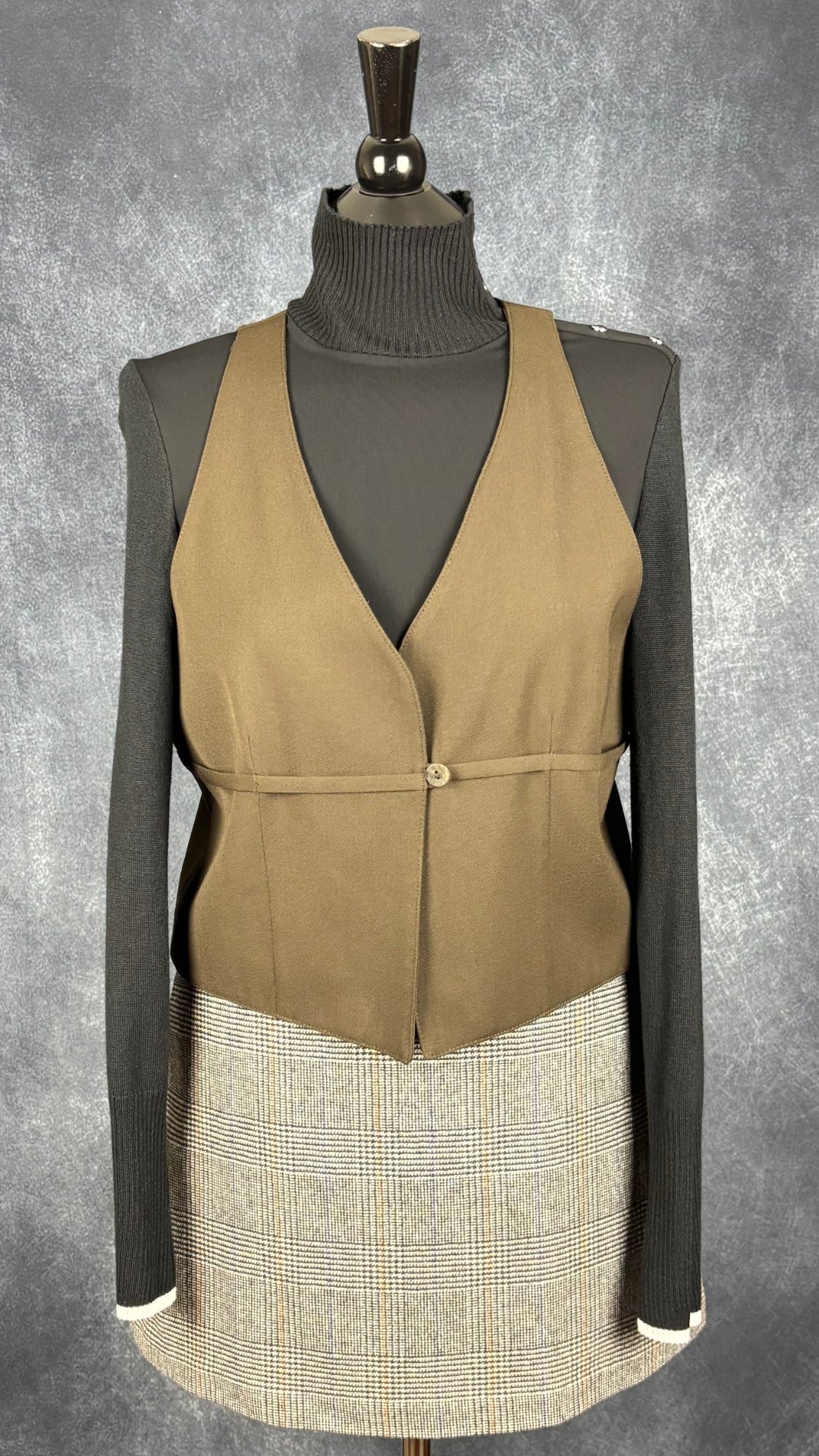 Gilet sans manches en laine vintage Tristan & Iseut, taille large (m). Vue de l'agencement avec la jupe à carreaux Wilfred et le chandail noir I by Iris Setlakwe.