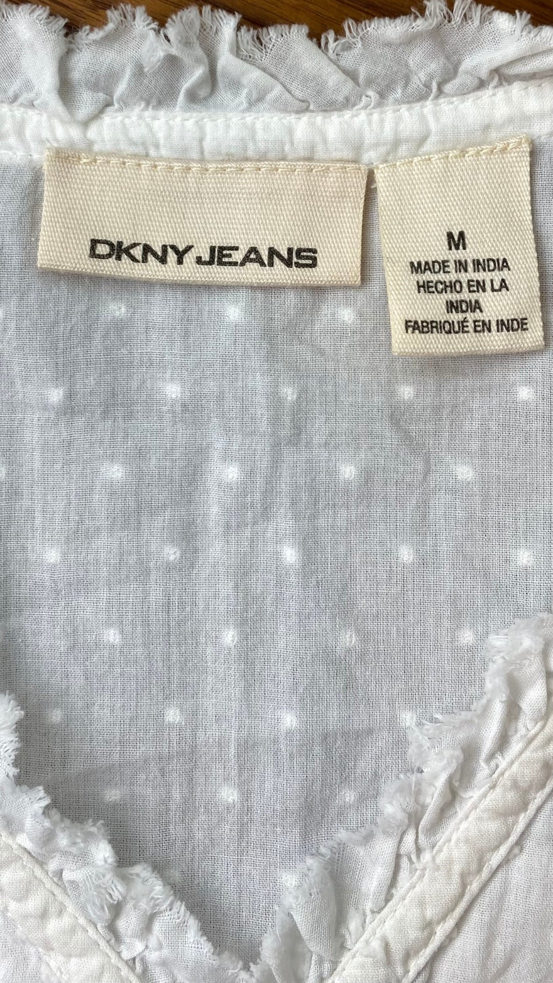 Haut ample crème avec détails DKNY jeans, taille medium. Vue de l'étiquette de marque et taille.