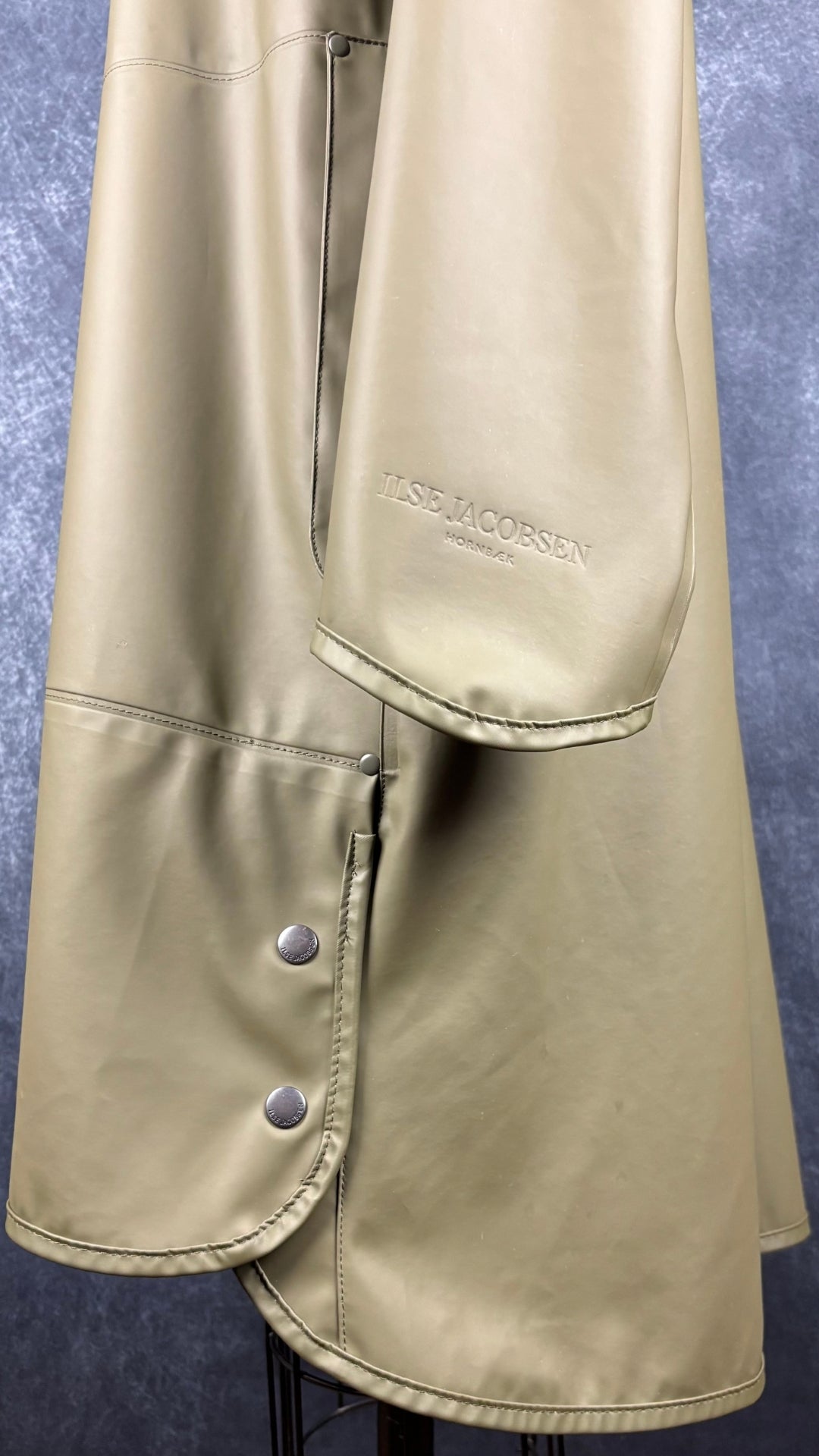 Imperméable vert olive Isle Jacobsen, taille 36 (s). Vue de près des boutons pour plus d'aisance à l'ourlet.
