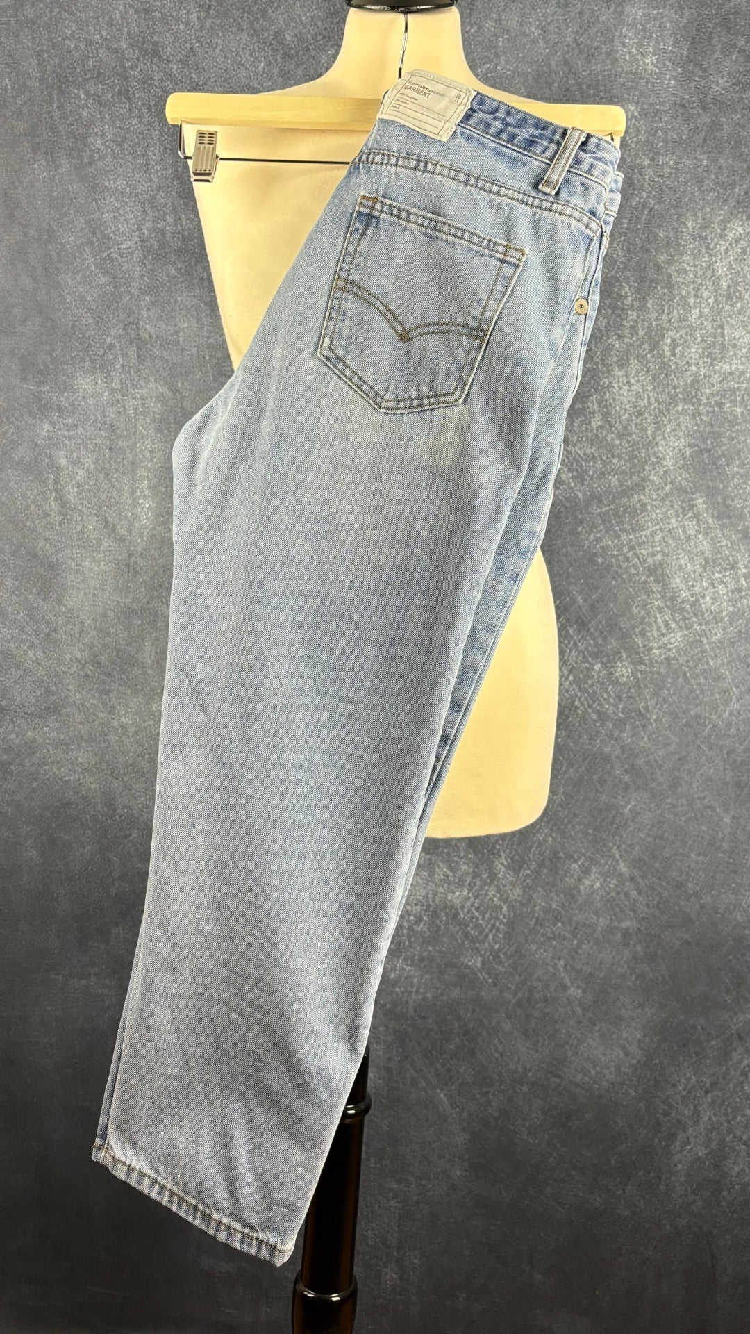 Jeans court taille croisée bleu pâle, R13, taille 28. Vue de côté du jeans sur un cintre.