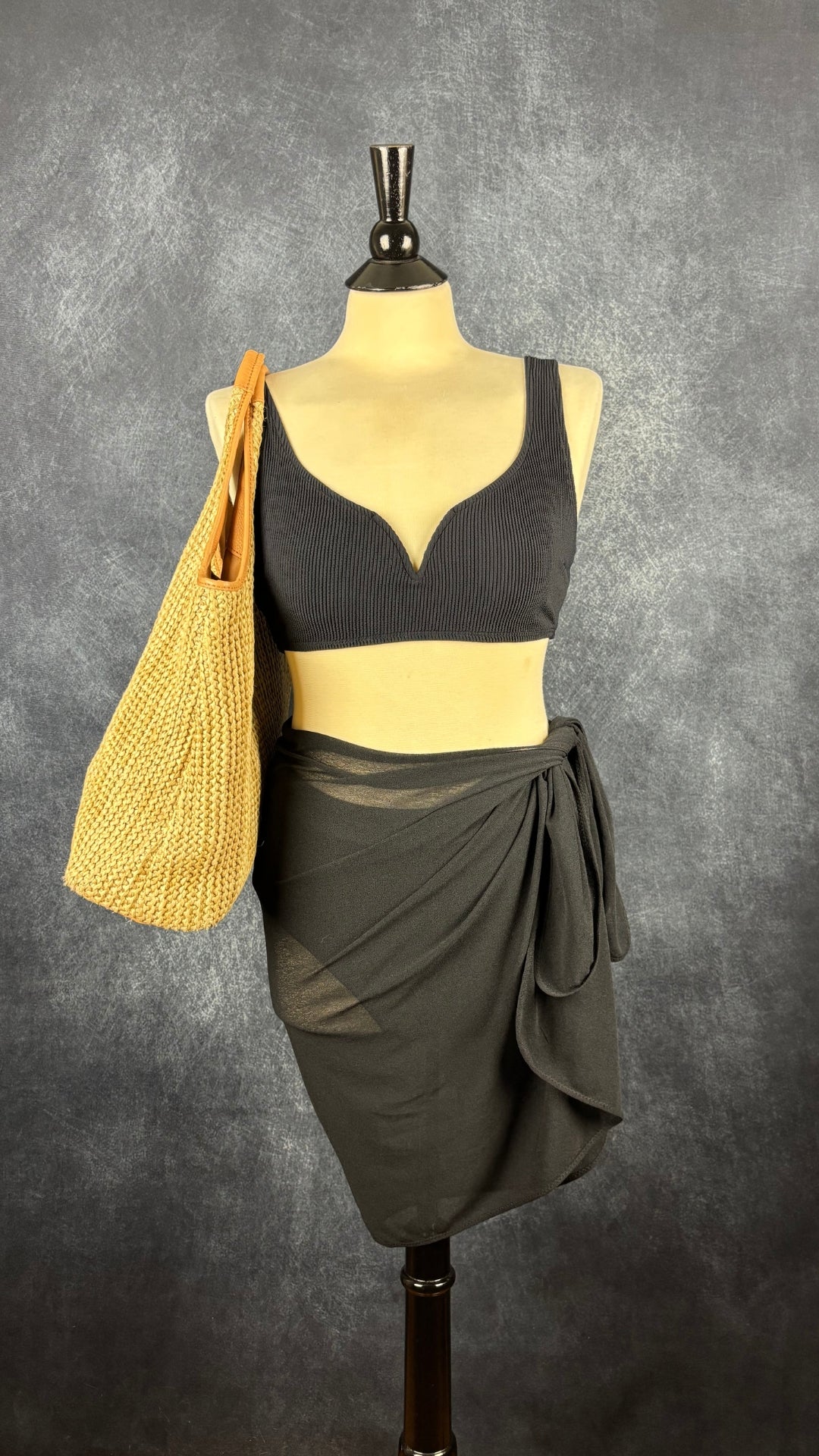 Jupe paréo noire Shan taille unique. Vue de face, sur le mannequin avec maillot de bain et sac en paille.