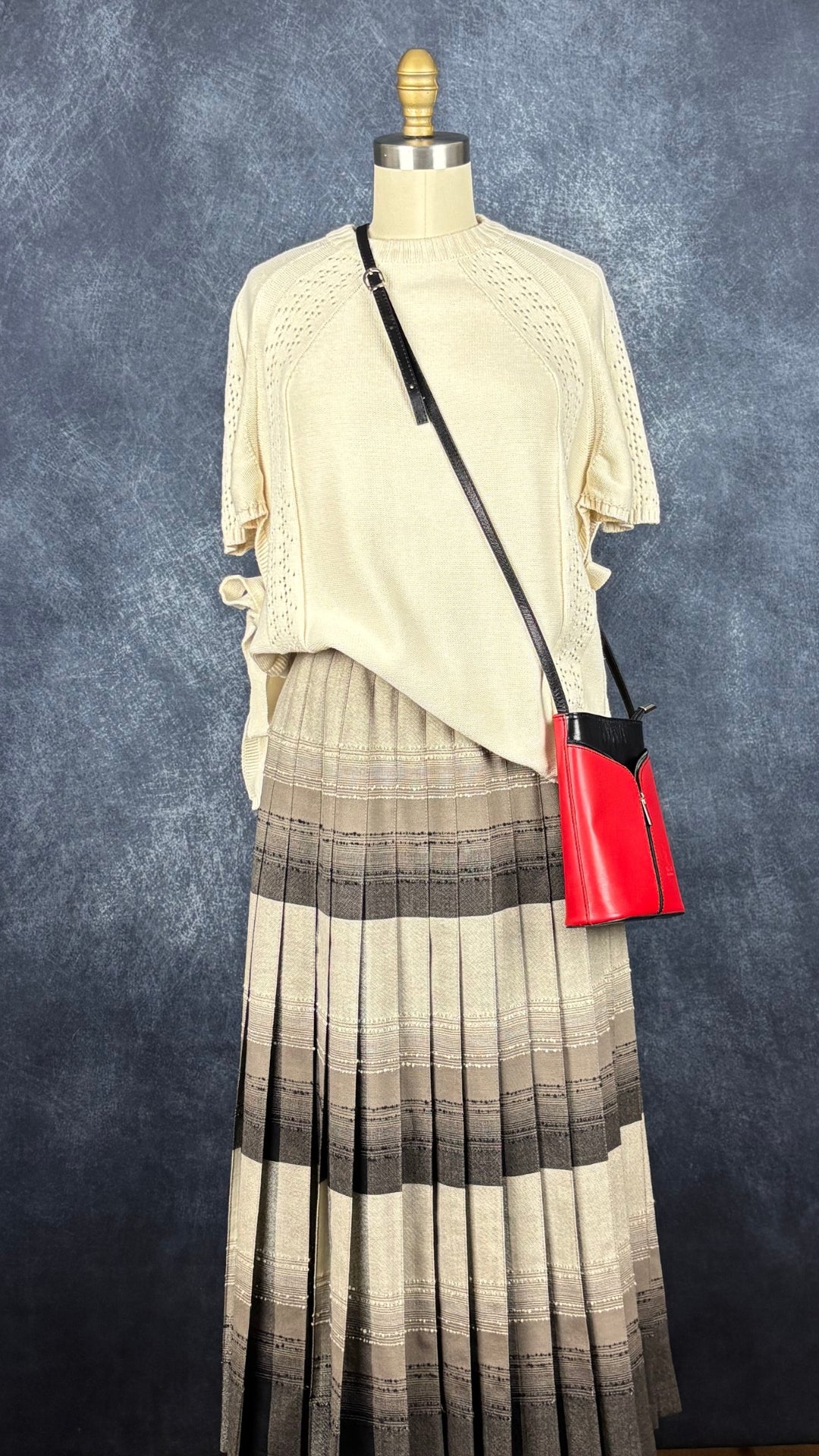 Jupe plissée vintage à carreaux réversible en laine Highland Queen, taille estimée à xs. Vue de l'agencement avec le chandail crème Dailystory et le sac en cuir rouge et noir.