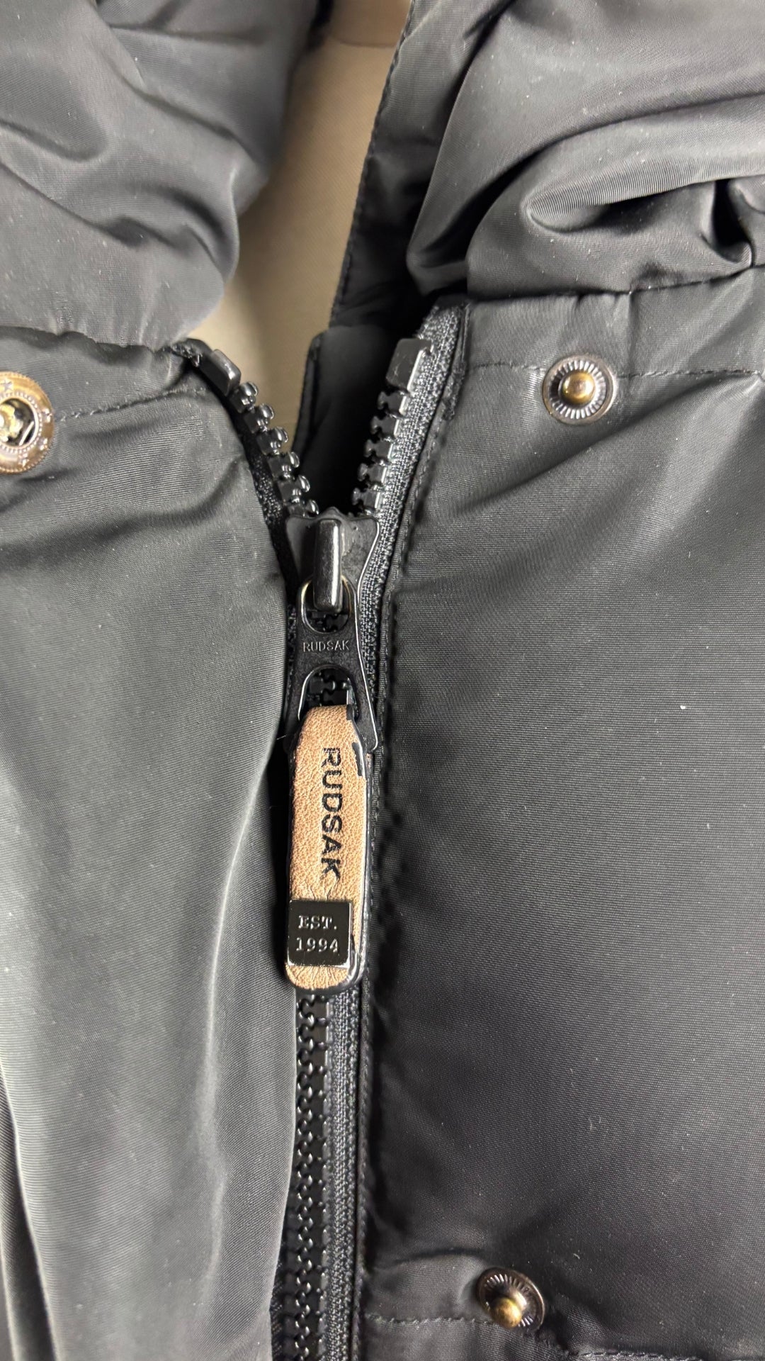 Manteau isolé en duvet mi-long noir avec détails en cuir, Rudsak, taille xs qui fait aussi small. Vue de près du curseur en cuir de la fermeture à glissière.