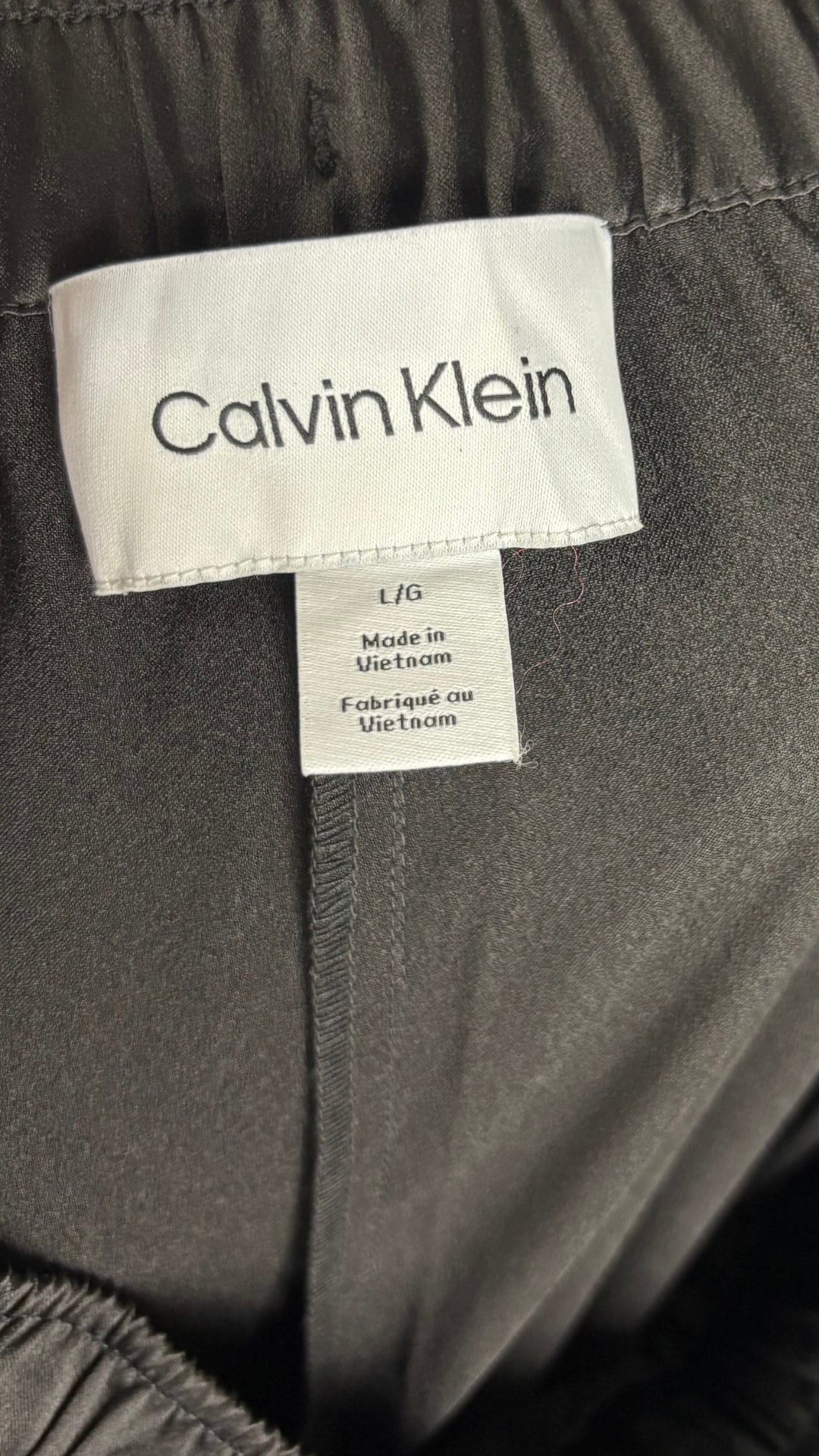 Pantalon satiné noir à jambes larges Calvin Klein, taille large. Vue de l'étiquette.