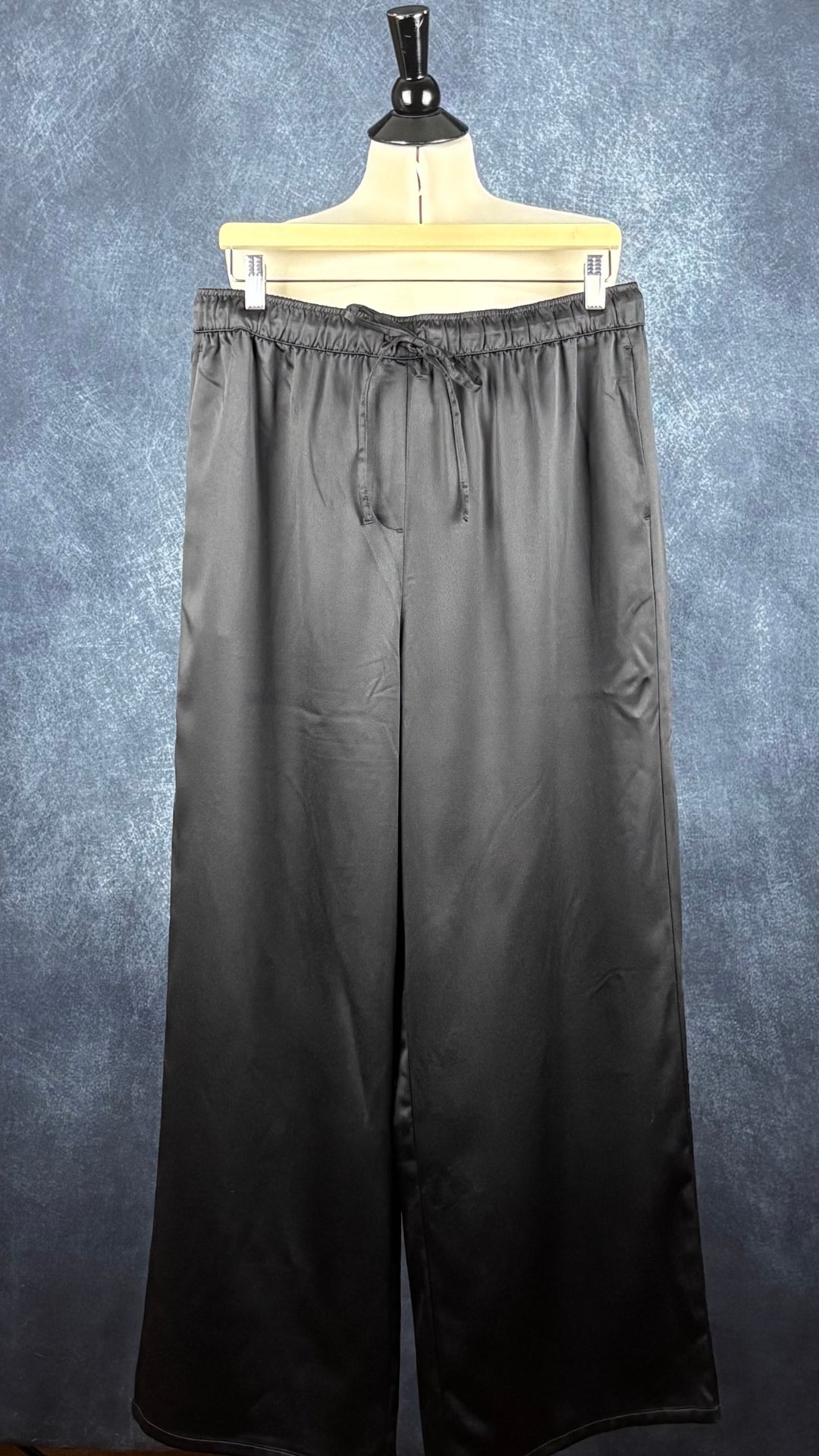 Pantalon satiné noir à jambes larges Calvin Klein, taille large. Vue de face sur un cintre.