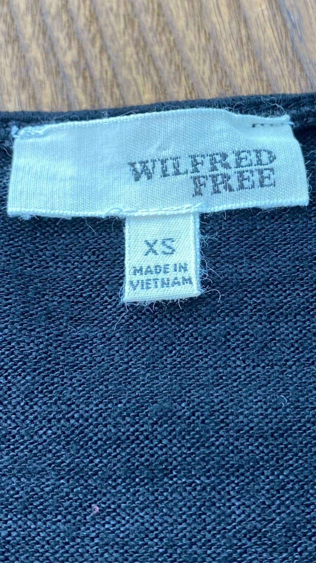 Robe ample en tricot noir Wilfred Free de Aritzia, taille xs (peut aussi faire small). Vue de l'étiquette de marque et taille.