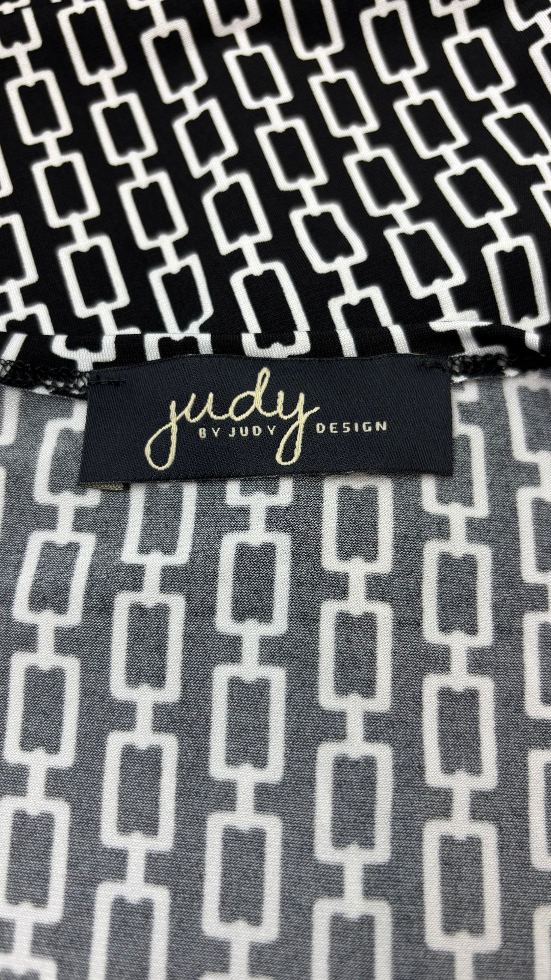 Robe noire à motifs géométriques écru, nouée à l'avant, Judy Judy Design, taille estimée à small/medium. Vue de l'étiquette.