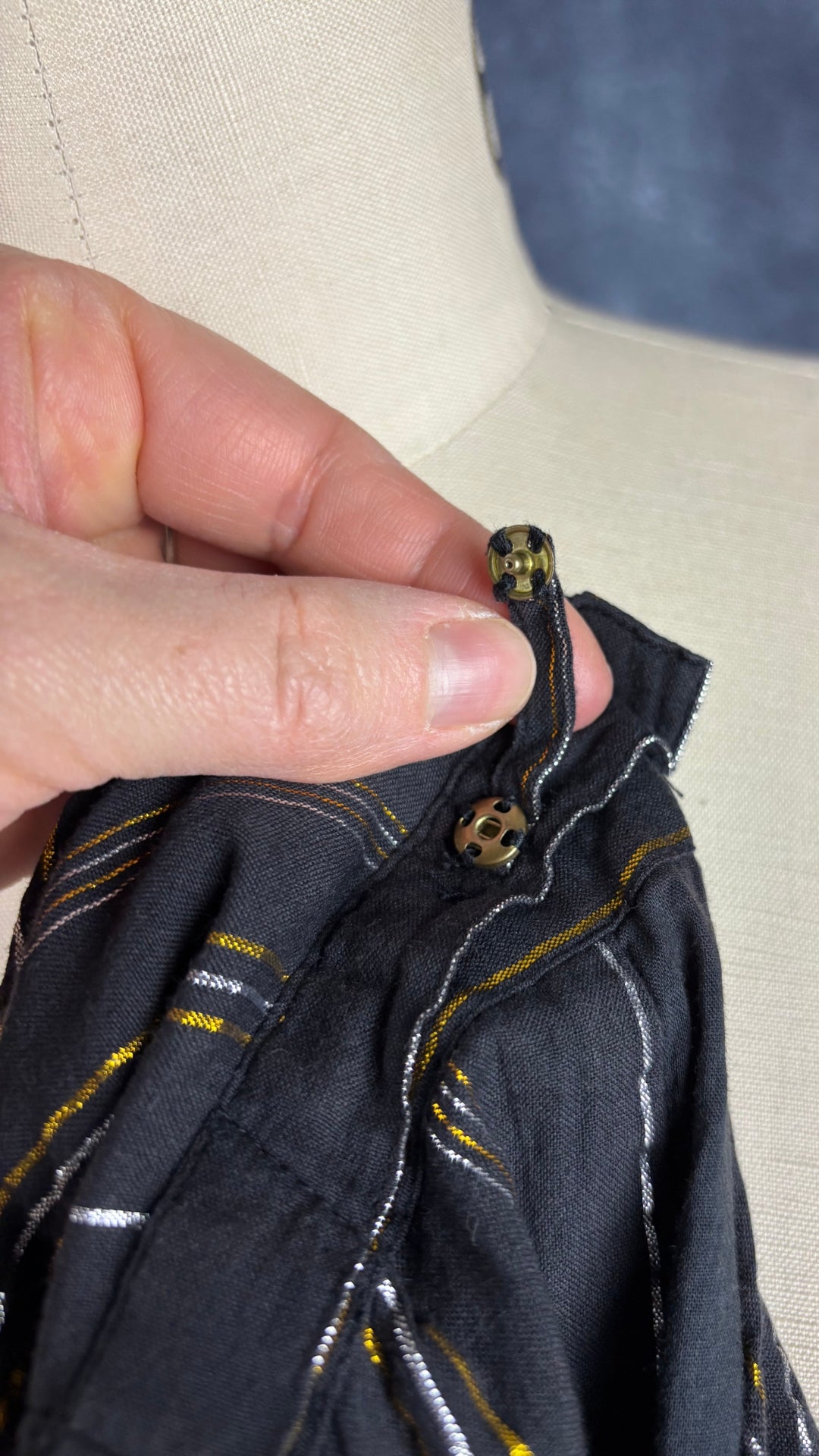 Robe noire à rayures or et argent Scotch & Soda, taille estimée à medium. Vue de près du bouton-presssion qui sert à maintenir les bretelles du soutien-gorge en place.