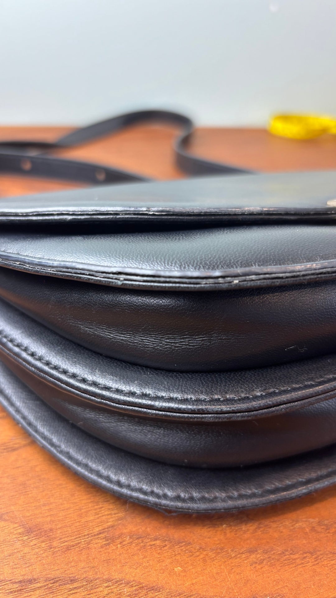 Sac en cuir lisse en demi-lune avec courroie type bandoulière, Flattered. Vue de près du coin droit du sac à main.