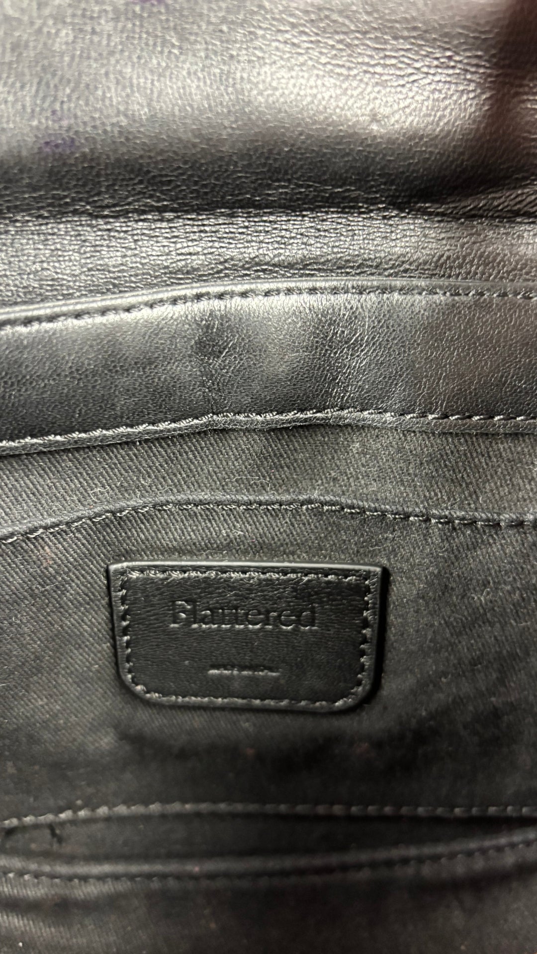 Sac en cuir lisse en demi-lune avec courroie type bandoulière, Flattered. Vue de l'étiquette intérieure du sac.