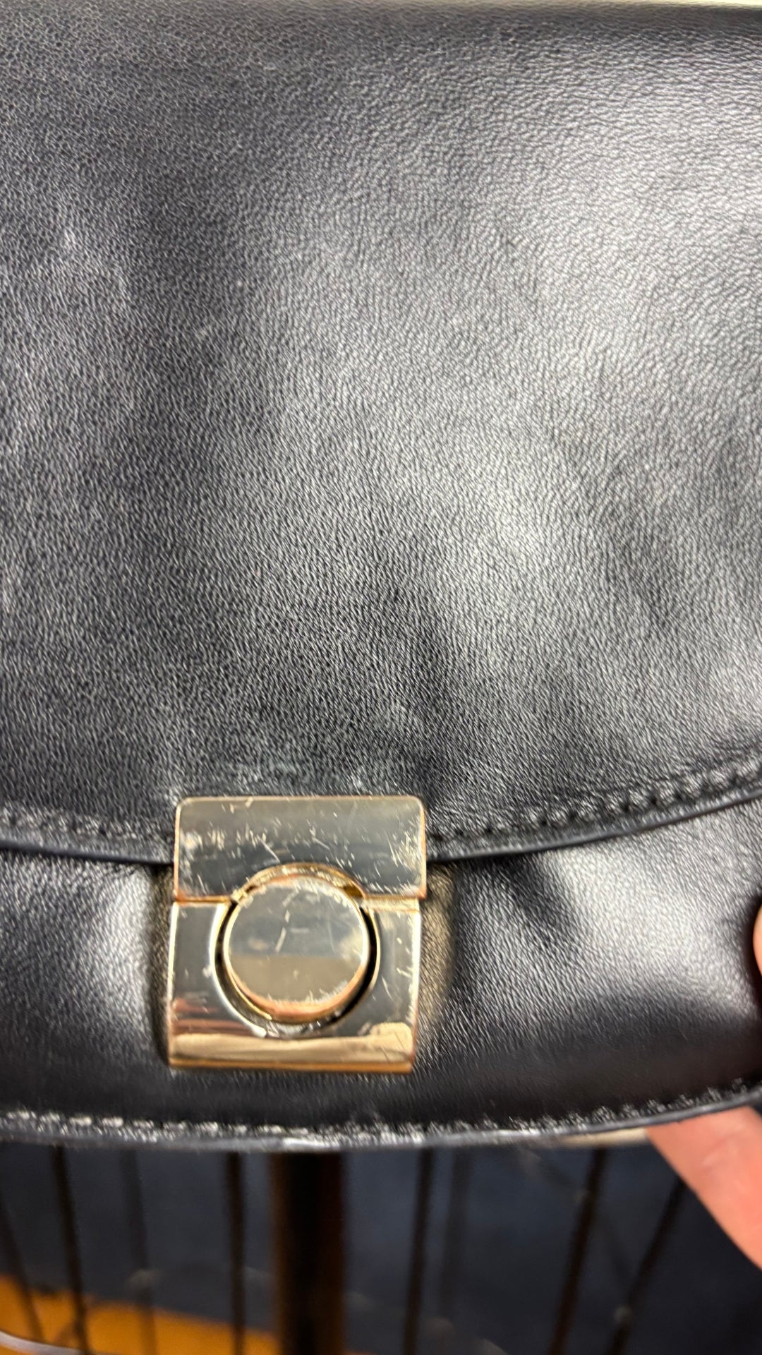 Sac en cuir lisse en demi-lune avec courroie type bandoulière, Flattered. Vue de très près du fermoir du sac et de ses égratignures.