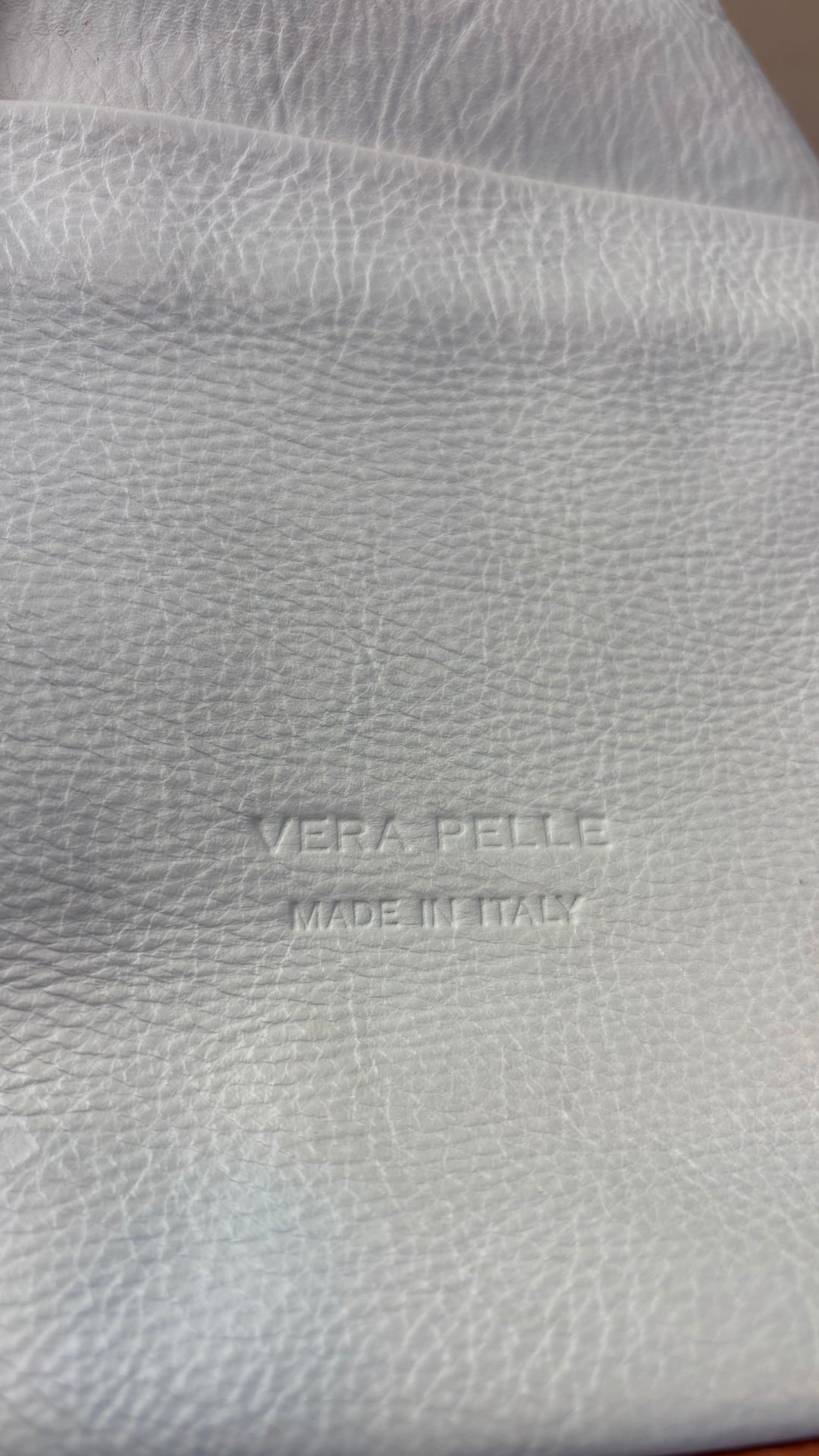 Sac à dos en cuir souple beige crème et brun tan Vera Pelle, fabriqué en Italie. Vue de près du logo gravé dans le cuir.