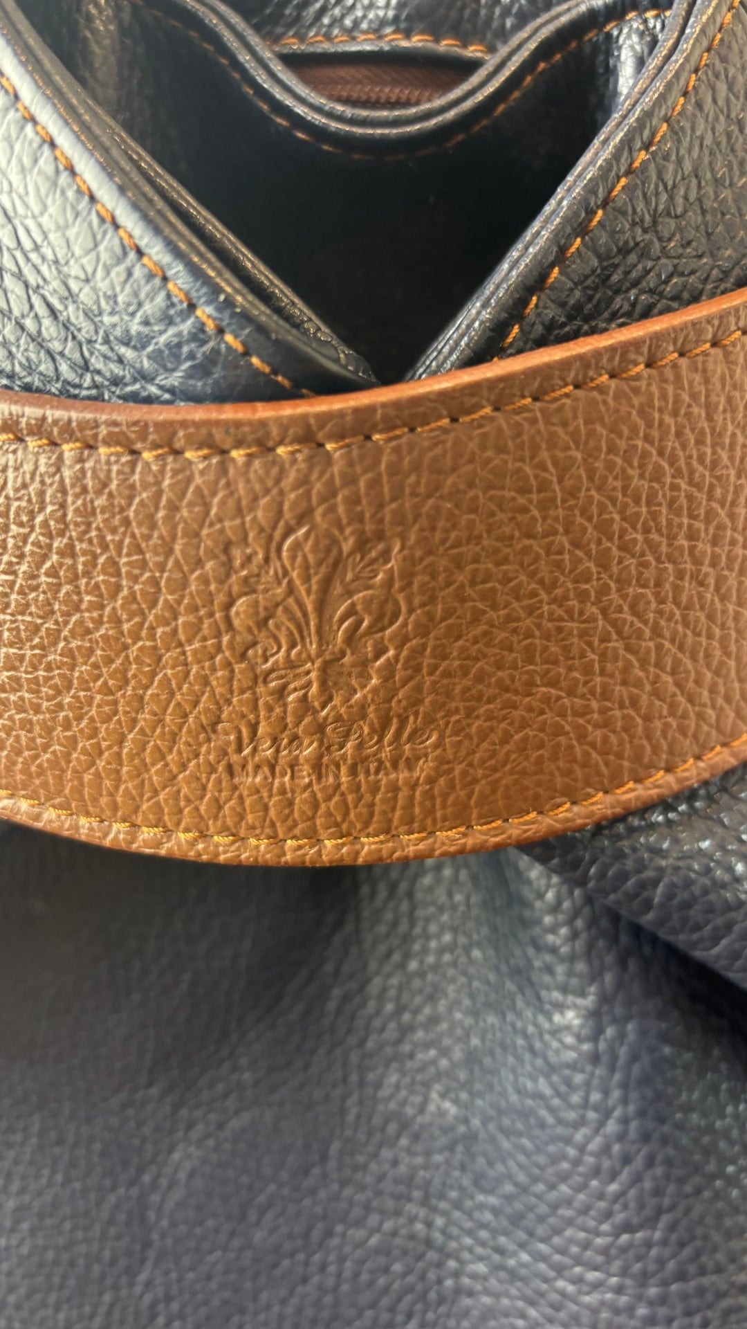 Sac à dos marine et brun en cuir Vera Pelle. Vue de près de la bande brune qui referme le sac.