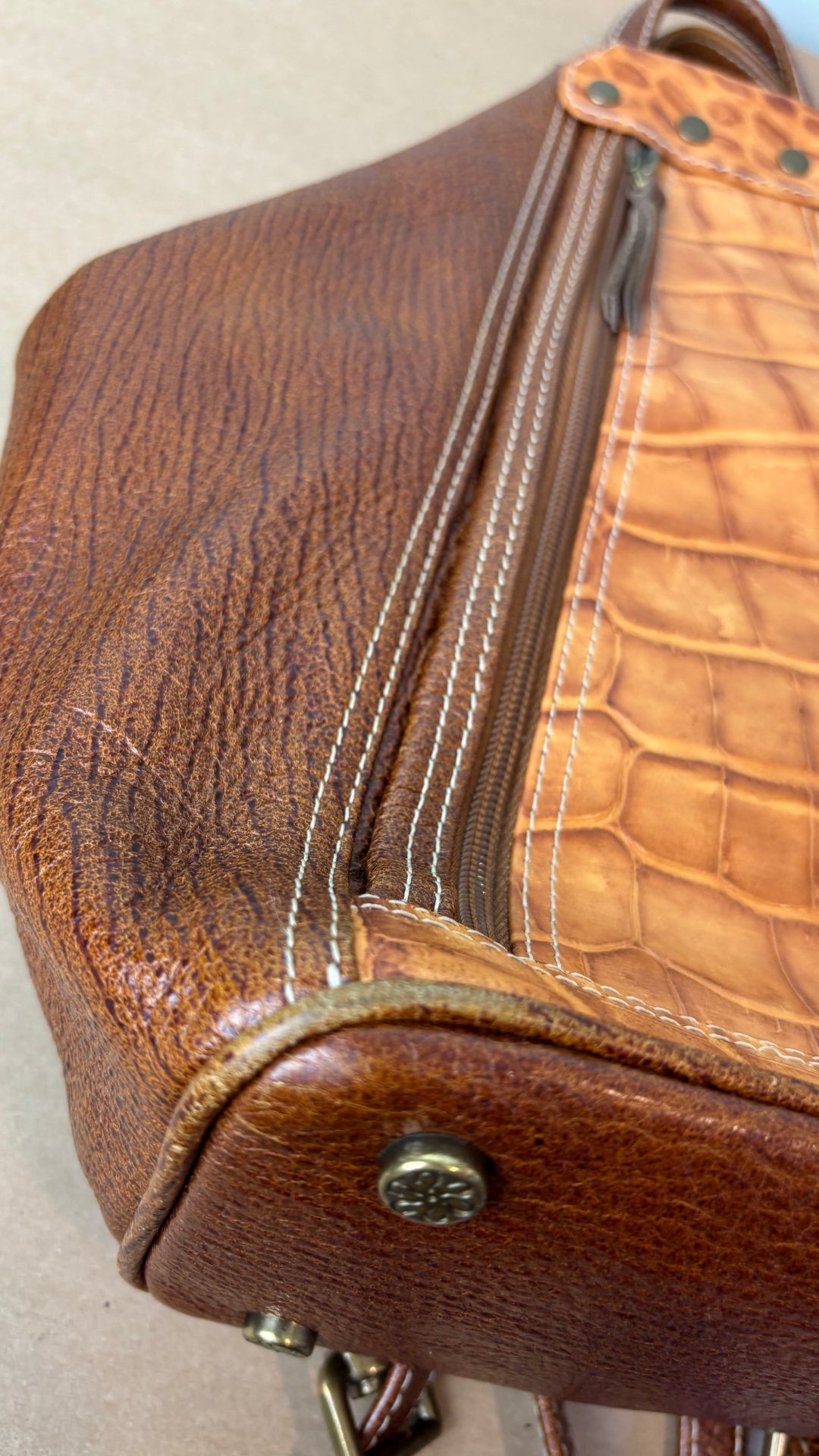 Sac à dos en cuir texturé brun et tan Matteo Mio. Vue de près d'un coin de la base légèrement usé.