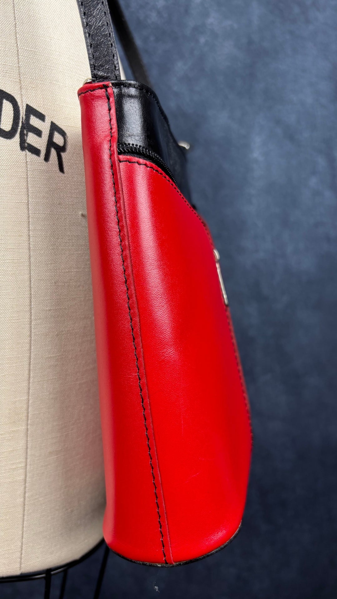 Sac à main en cuir noir et rouge à bandoulière Vera Pelle avec base ovale Vera Pelle. Vue de côté du sac.