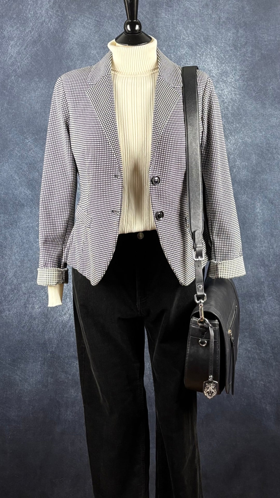 Sac à main en cuir noir Rudsak de taille moyenne avec coins de la base arrondis. Vue de l'agencement avec le pantalon noir en velours côtelé Part Two, le col roulé crème et le blazer Imperial.