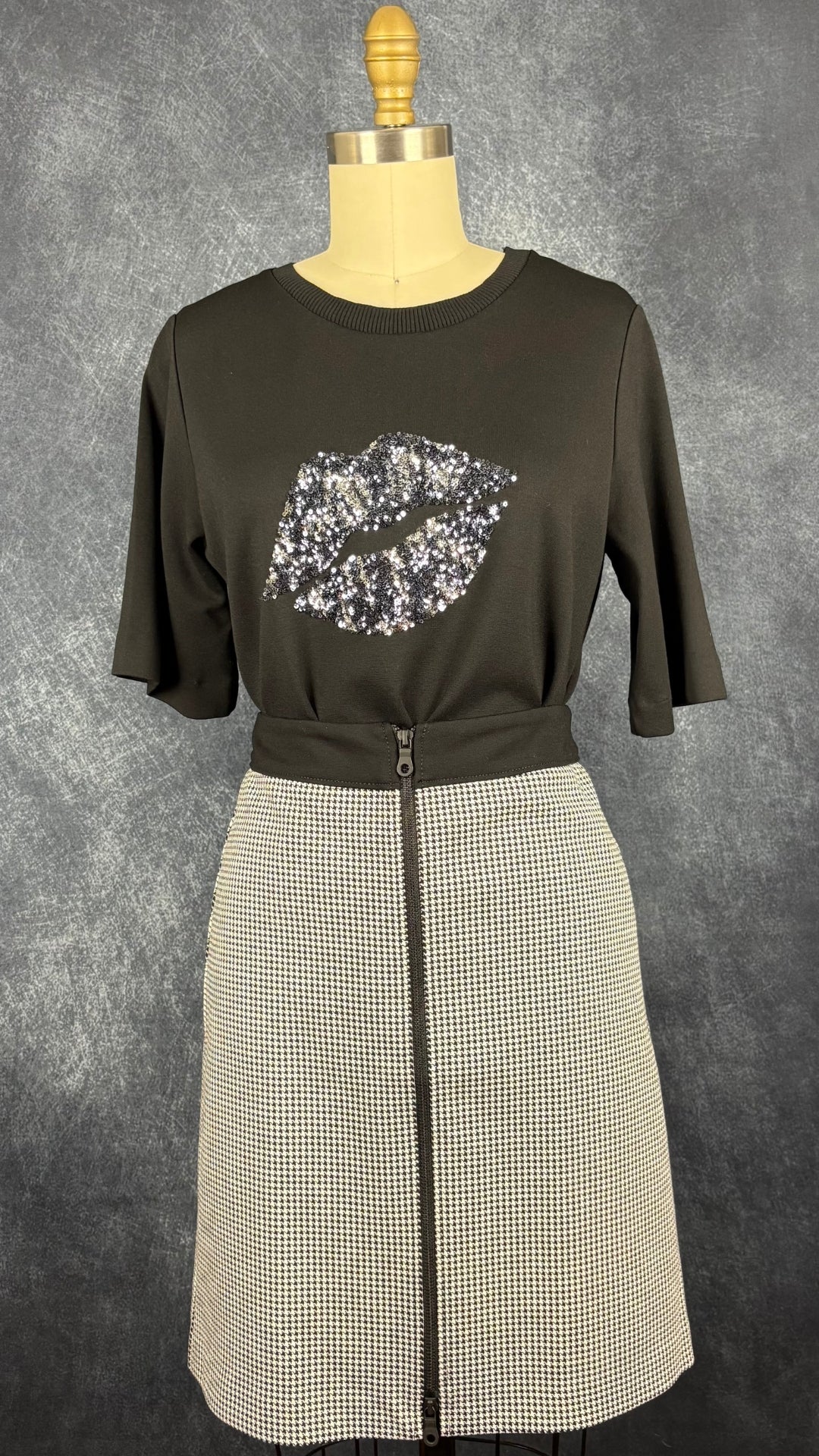 T-shirt noir avec lèvres en sequins au centre, InWear, taille small. Vue de l'agencement avec la jupe à motifs pied de poule et fermeture à glissière centrale Tristan.