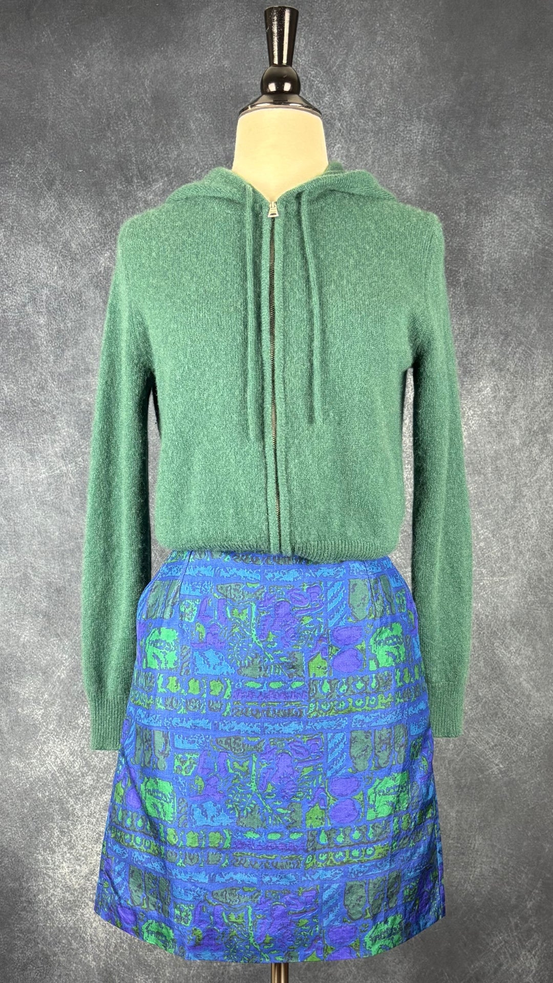 Veste en cachemire à capuchon vert forêt The Group by Babaton, taille small. Vue de l'agencement avec la jupe colorée à poches.