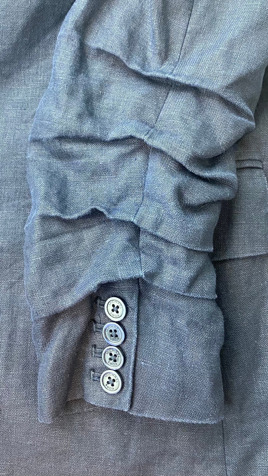 Veston estival parfait, ce blazer marine en lin Michael Kors est une base pour les températures chaudes. Vue du détail de la manche froncée.