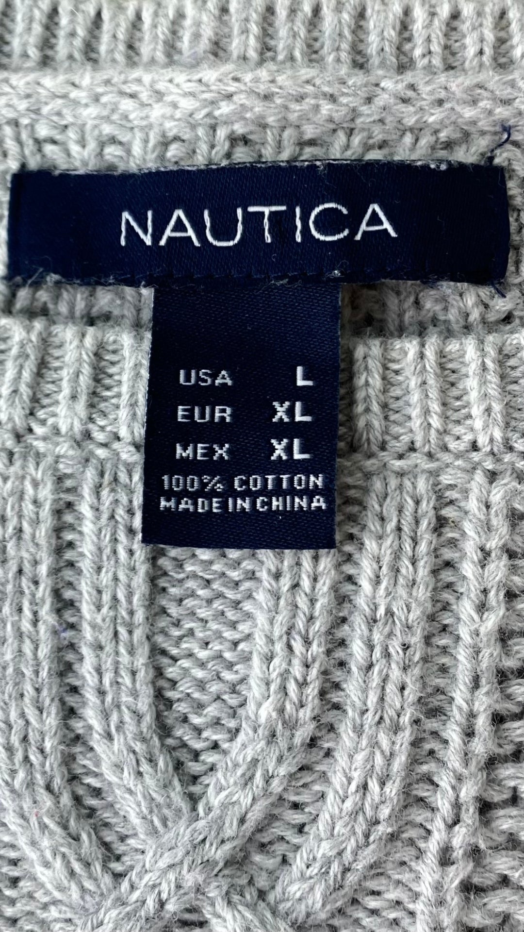 Chandail en tricot gris Nautica avec de magnifiques torsades aux manches et sur le devant. Vue de l'étiquette de marque, taille et composition.