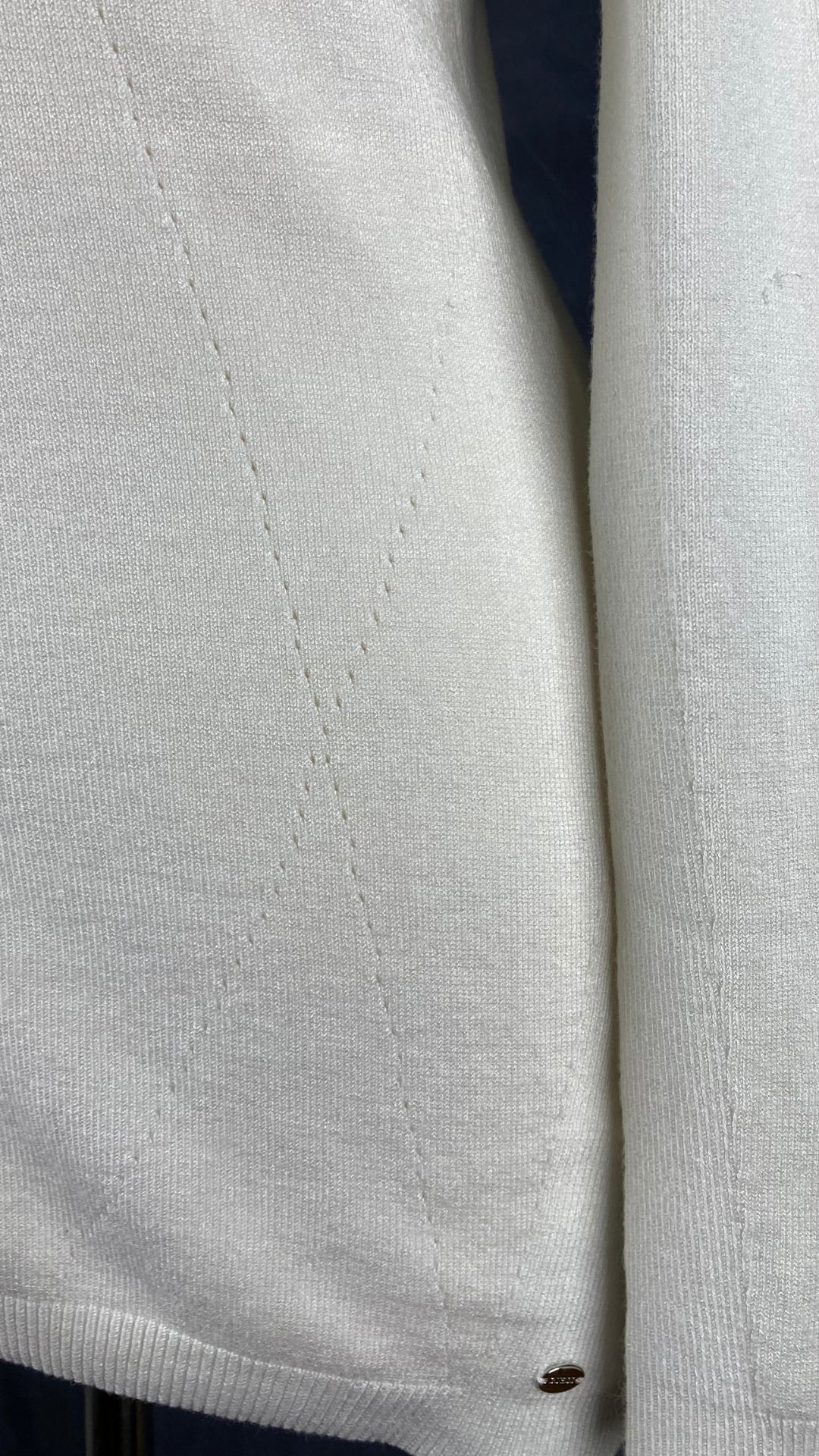 Chandail crème en tricot Guess à une manche. Vue de près des détails du tissu.