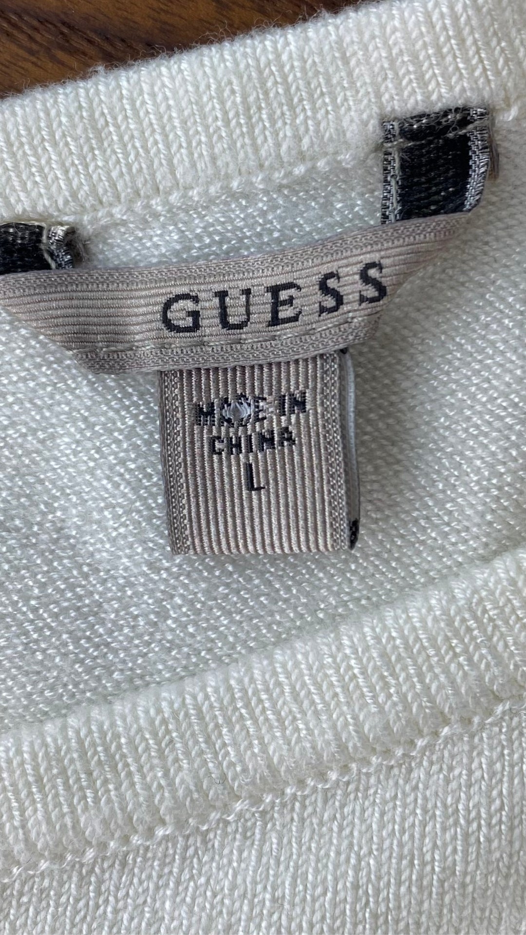 Chandail crème en tricot Guess à une manche. Vue de l'étiquette de marque et taille.