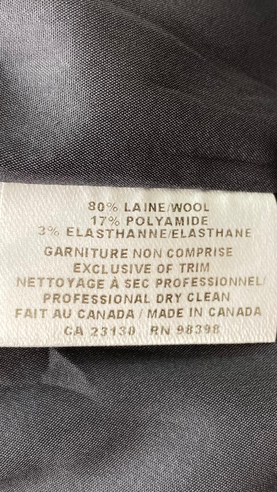 Jupe crayon en lainage gris faite au Canada. Zip au dos pour la fente d'aisance. Vue de l'étiquette de composition et entretien.
